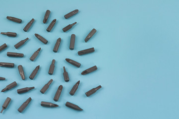 Scattered metal bits for screwdriver in form of triangle on blue background with copy space