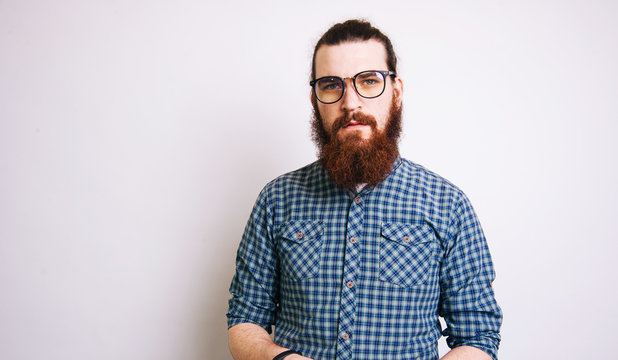 Portrait of serious bearded man in casual looking confident at the camera over white background
