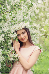 Spring woman outdoors on flowers background. Pretty young female model resting in blossom spring flowers garden