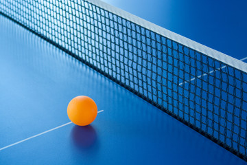 yellow ball for table tennis lies on a blue table