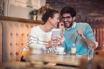 Young couple in indoor cafe using digital tablet