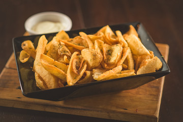 Rustic fries served on a square plate in black color