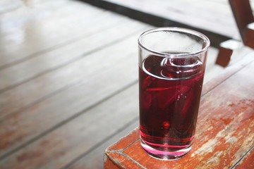 Glass of soft drink with ice on wood table background