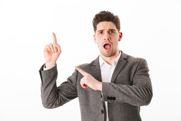 Shocked business man in jacket pointing up and away