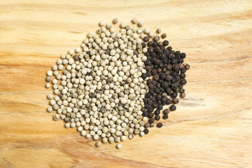 bunch of white and black peppercorns on a wooden kitchen board
