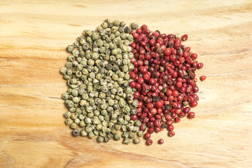 bunch of green and red peppercorns on a wooden kitchen board
