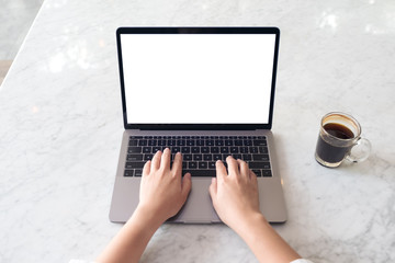 Top view mockup image of hands using laptop with blank white desktop screen and coffee cup on marble table in cafe