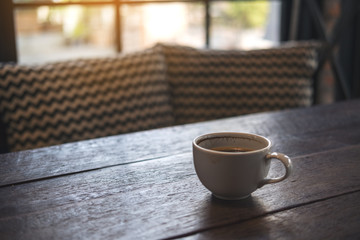 Closeup image of hot coffee cup on vintage wooden table in cafe