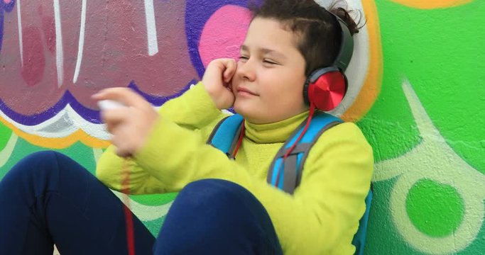 Portrait of a caucasion preteen boy with headphone listening to music and relaxing at the outdoor
