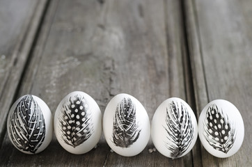 Easter white eggs decorated with feather isolated on grey rustic background