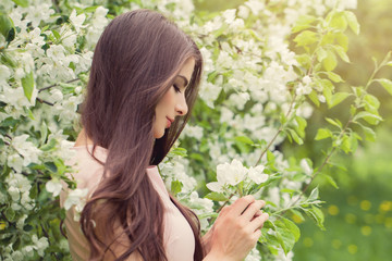 Flowers woman in blossom spring garden. Fashion Model Girl wich spring flowers on green nature background