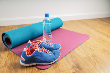 Sport shoes & bottle of water on yoga mat. Healthy lifestyle conceptual. Blue sneakers on a wooden...