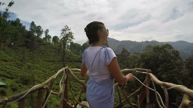 A woman looks at the tea plantations in Sri Lanka, beautiful fence in front