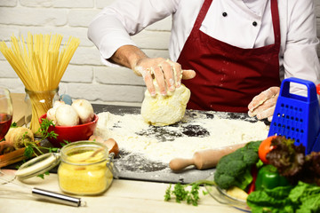 Male hands work with kneaded dough on white brick background