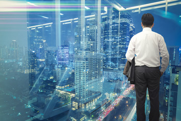 Business vision concept. Backside businessman standing and looking out to modern business district...