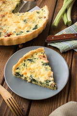 Spinach, onion and bacon tart on wood background