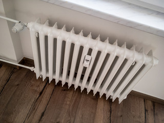 Old white radiator with an adjustment valve