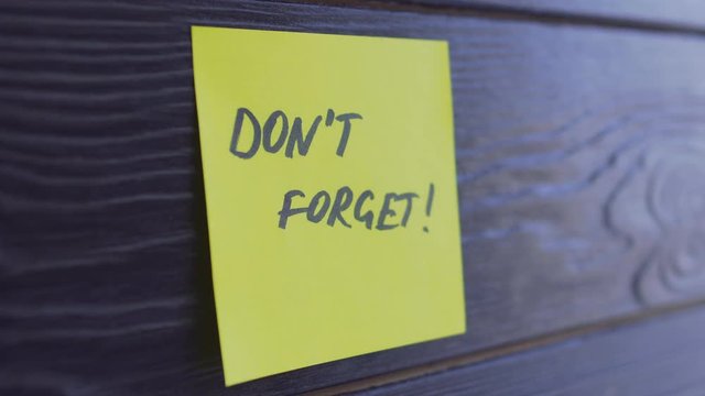 Don't forget written on yellow paper sticker notes over wooden background