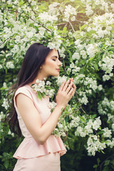 Perfect young woman smelling flower in blossom spring flowers garden background