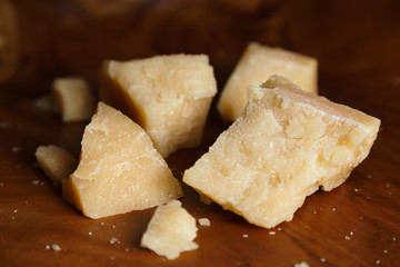 Parmesan cheese on a wooden board. Pieces of cheese close-up.