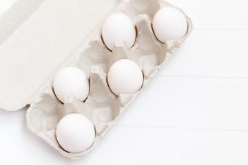 white chiken eggs on white wood background