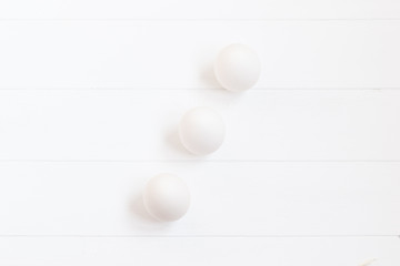 white chiken eggs on white wood background