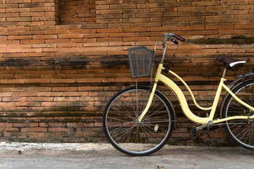 Fototapeta na wymiar yellow bicycle parking near Thai traditional brick wall