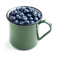 blueberries on green enamel  mug cup. isolated white background