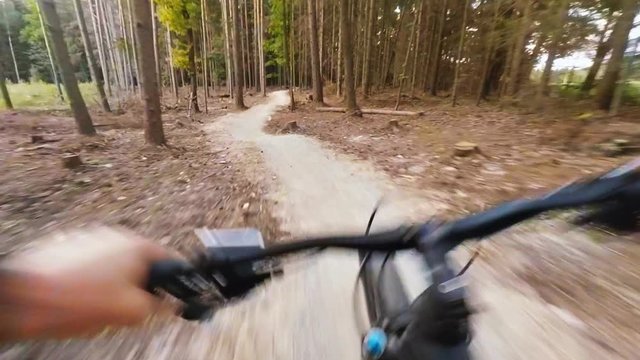 Sunset mountain bike riding in green woods on double track long road. Forest extreme speed cycling, first person perspective view POV. Gimbal stabilized video GOPRO HERO4 4K.