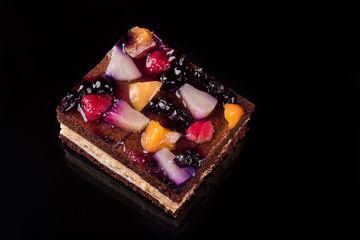 Piece of fruit cake with jelly and cream. Black background. Top view