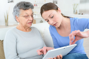 teenage granddaughter showing grandmother how to use digital tablet - obrazy, fototapety, plakaty