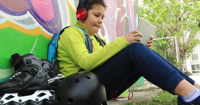Young preteen boy with headphone  using digital tablet computer at the outdoor