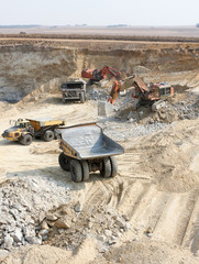 Open Pit Coal Mining - Large Rock Dump Trucks and Excavators digging and hauling in an open pit...