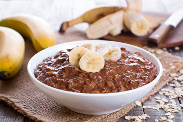 Chocolate oatmeal with banana in white bowl for breakfast