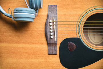 Naklejka premium Classic and music style. Acoustic guitar background with headphone music and guitar pick. Musical mood induction background.
