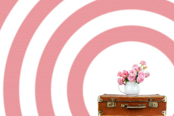 Pink flowers in jug on old brown vintage suitcase. Roses in jug. Pink roses. Shabby chic.