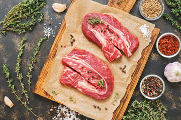 Raw beef meat. Beef steaks on a cutting board. Dark rustic background, top view.