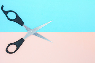 black scissors on blue and pink paper background