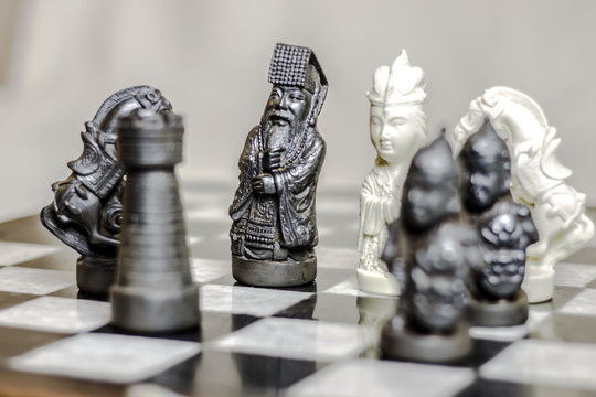 Chess game. Carved in stone chinese figures. Chess pieces on a chessboard.  Stock Photo | Adobe Stock