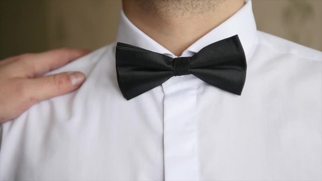 Friend fixing bowtie for the groom