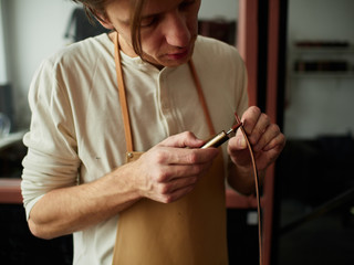 Painting the tip of the leather strap with a mechanical brush for painting the cuts of the leather saddles.