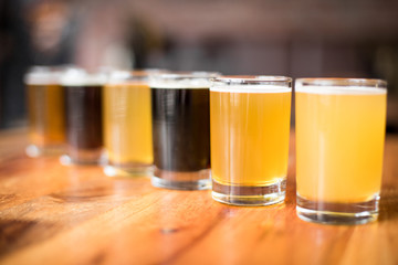 Side view on a flight of craft beer in pint glasses arranged in a diagonal row