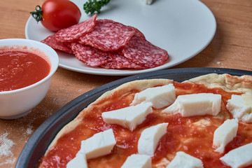 Homemade raw pizza pepperoni, ingredients for pizza, tomato sauce, mozzarella cheese, salami