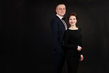 Elegance woman in black evening dress with man in suit posed on studio isolated on black. Duet couple of two.