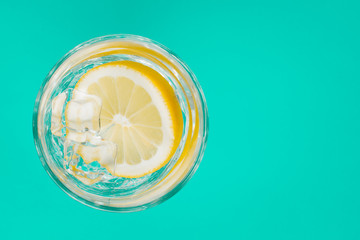 Drink, water with lemon in a glass, on a blue background.