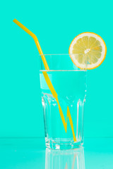 Drink, water with lemon in a glass, on a blue background.