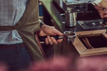 A professional barista making a coffee with the professional coffee machine, at the coffee shop.