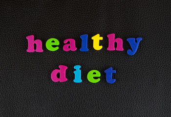 Healthy diet written in   a mix of colourful plastic letters  on black leather. 