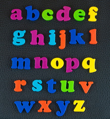 Alphabet plastic letters on the leather background.