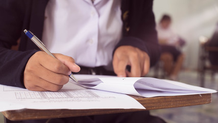 Close up to students writing and reading exam answer sheets exercises in classroom of school with stress.16:9 style